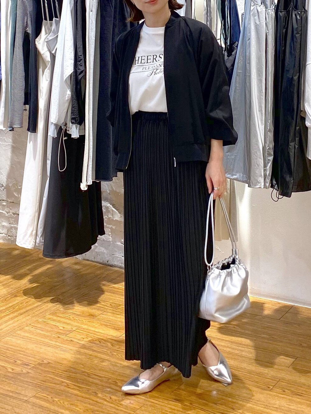 シルバー系のショルダーバッグ、ブラック系のスカート、グレー系のパンプスを着用したレディースの春コーディネートの2枚目の写真