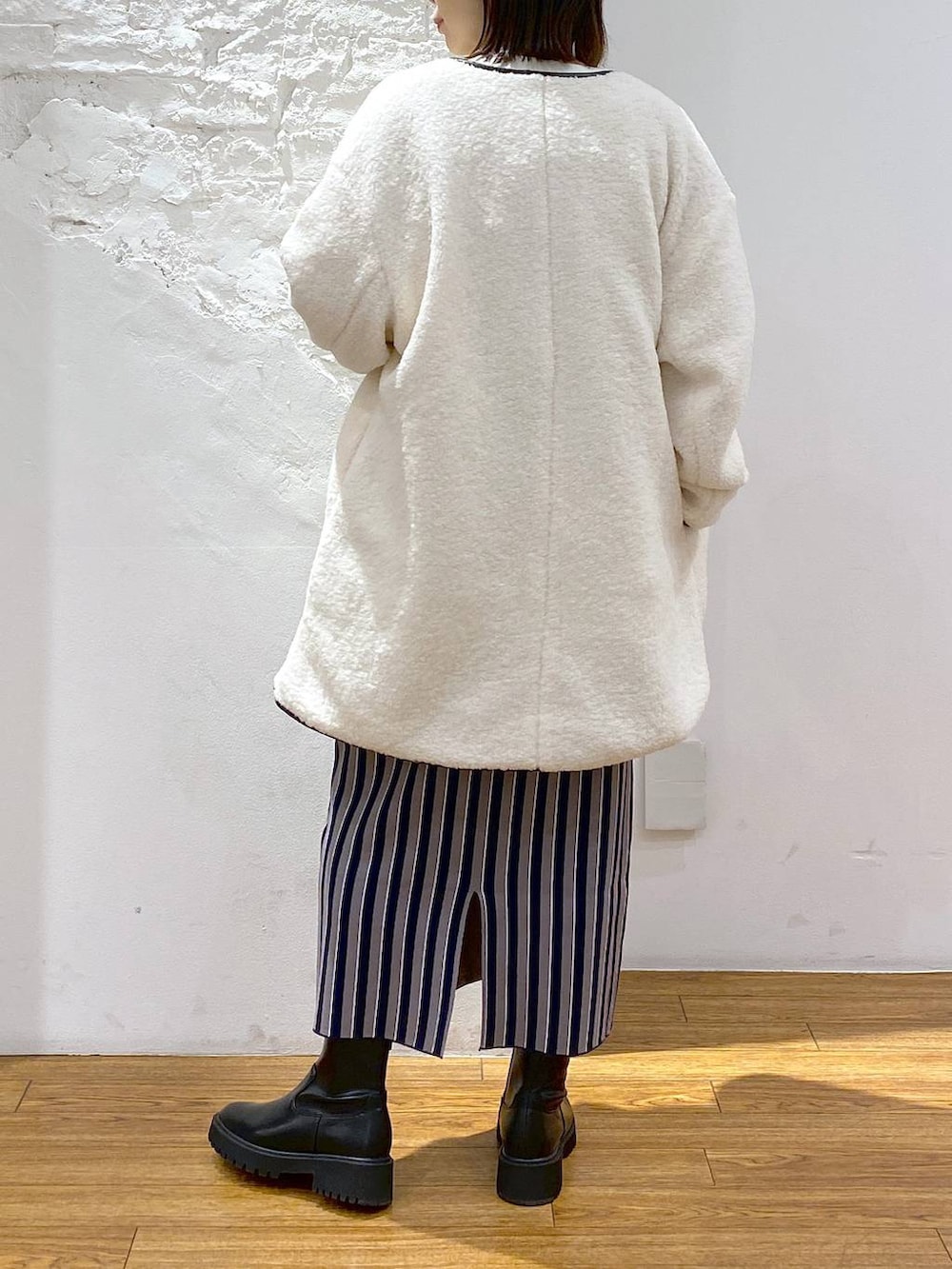 ブラック系のブーツ、ブルー系のスカート、ホワイト系のその他アウターを着用したレディースの冬コーディネートの4枚目の写真