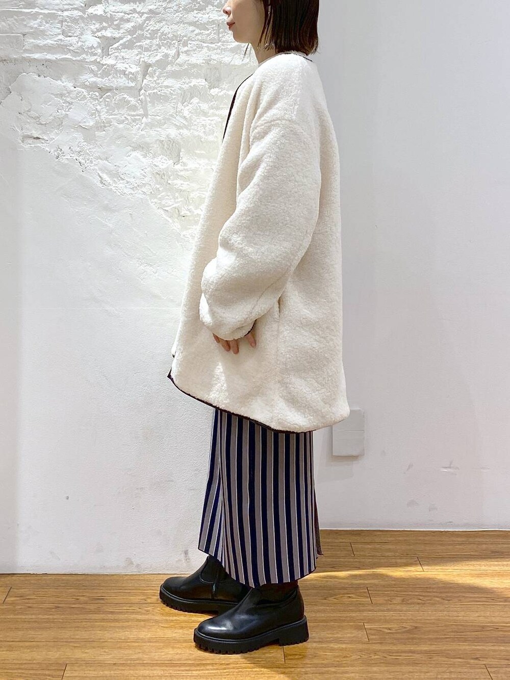 ブラック系のブーツ、ブルー系のスカート、ホワイト系のその他アウターを着用したレディースの冬コーディネートの3枚目の写真