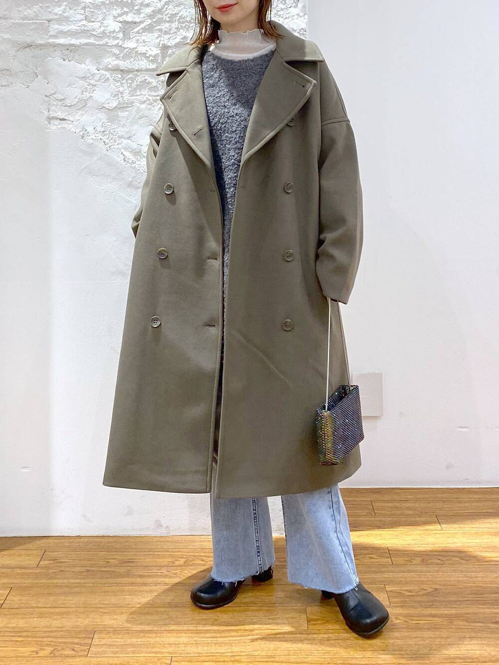 グリーン系のチェスターコート、グレー系のTシャツ/カットソー、ブラック系のブーツを着用したレディースの冬コーディネートの5枚目の写真