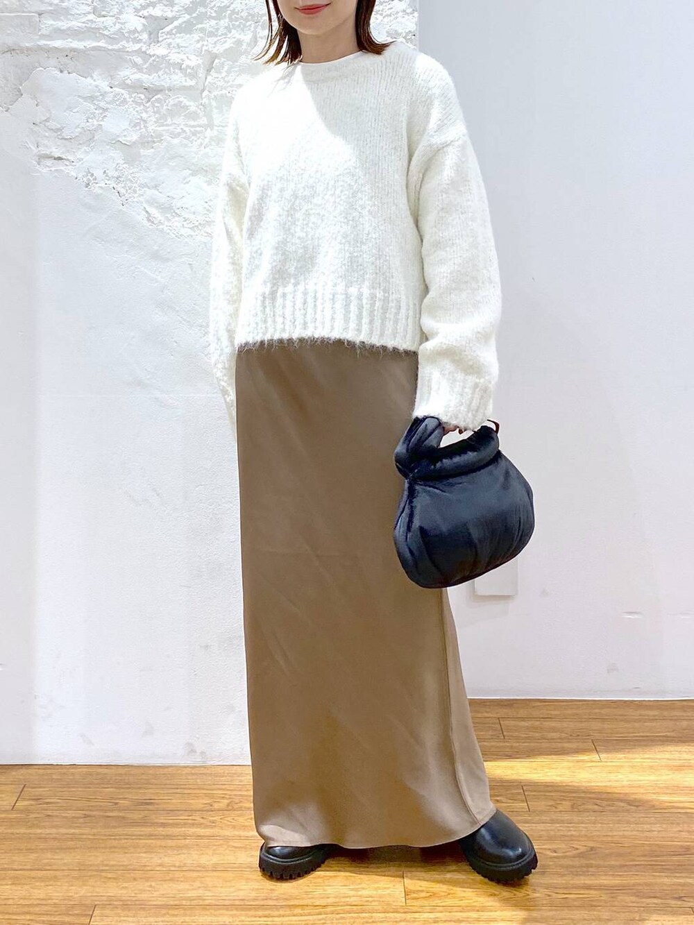 ブラック系のその他アウター、ブラック系のブーツ、ホワイト系のスカートを着用したレディースの冬コーディネートの3枚目の写真