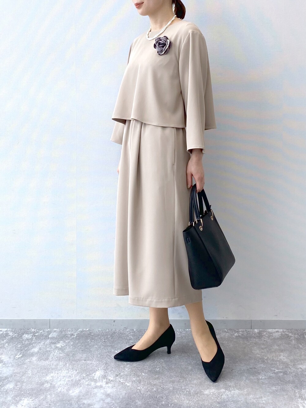 ベージュ系のワンピース、ブラック系のハンドバッグ、ブラック系のパンプスを着用したレディースの冬コーディネートの2枚目の写真