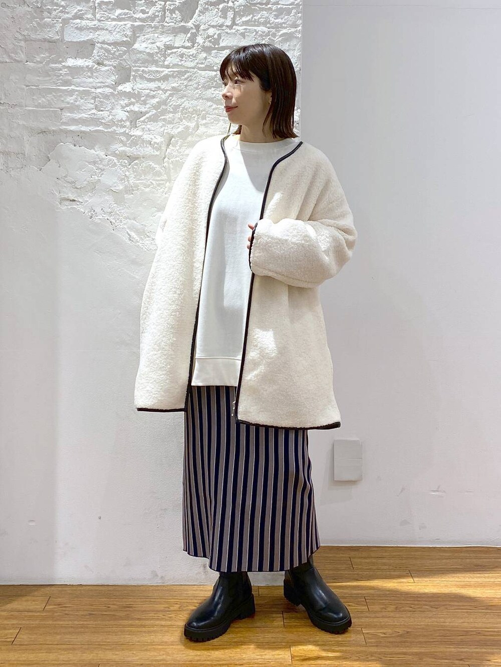 ブラック系のブーツ、ブルー系のスカート、ホワイト系のその他アウターを着用したレディースの冬コーディネートの5枚目の写真