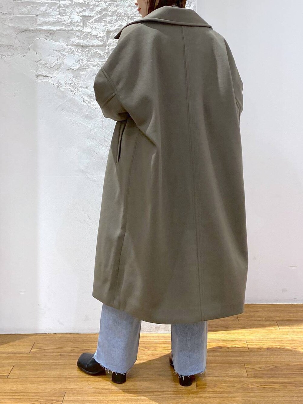 グリーン系のチェスターコート、グレー系のTシャツ/カットソー、ブラック系のブーツを着用したレディースの冬コーディネートの4枚目の写真