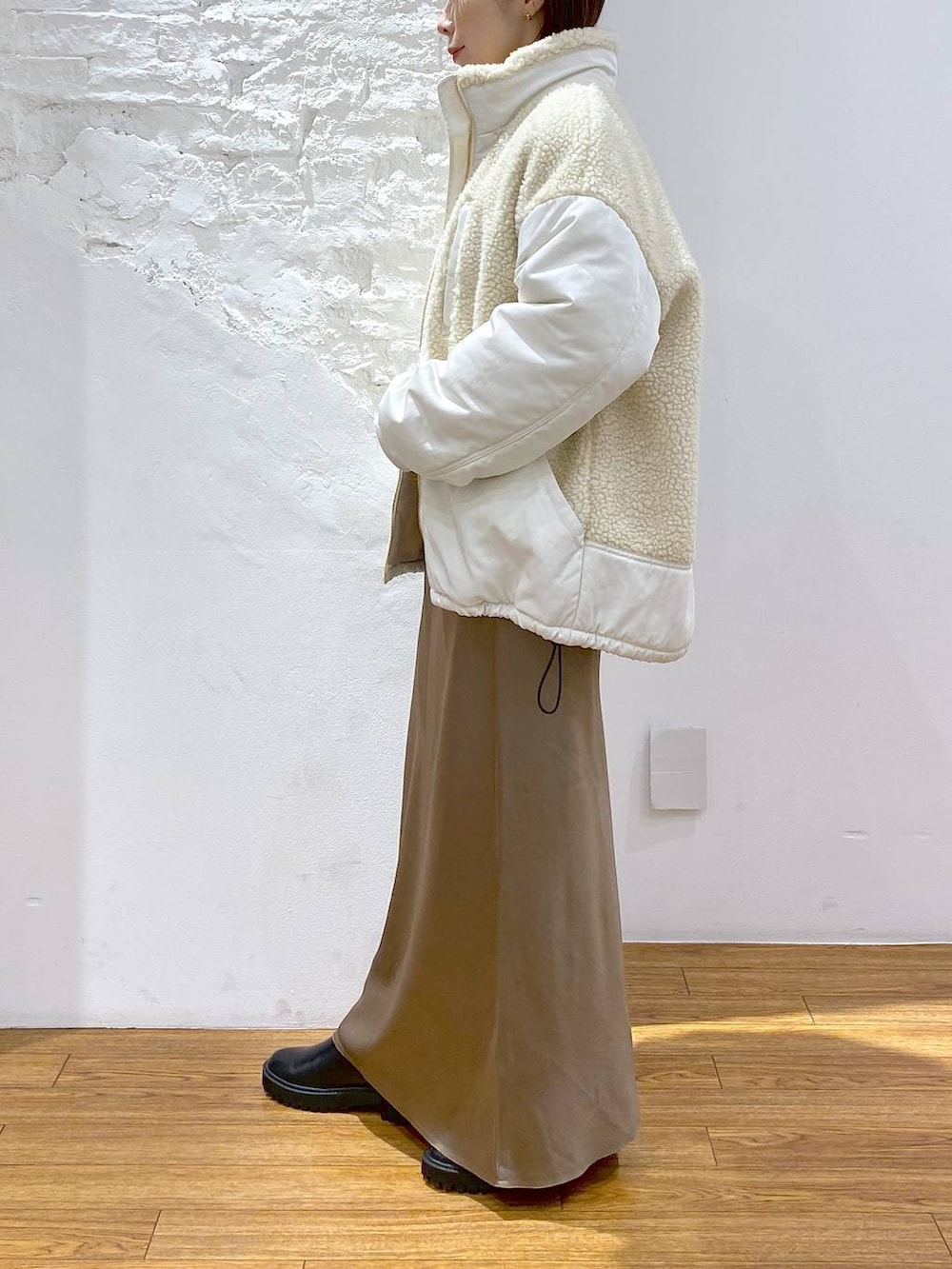 ブラック系のその他アウター、ブラック系のブーツ、ホワイト系のスカートを着用したレディースの冬コーディネートの2枚目の写真