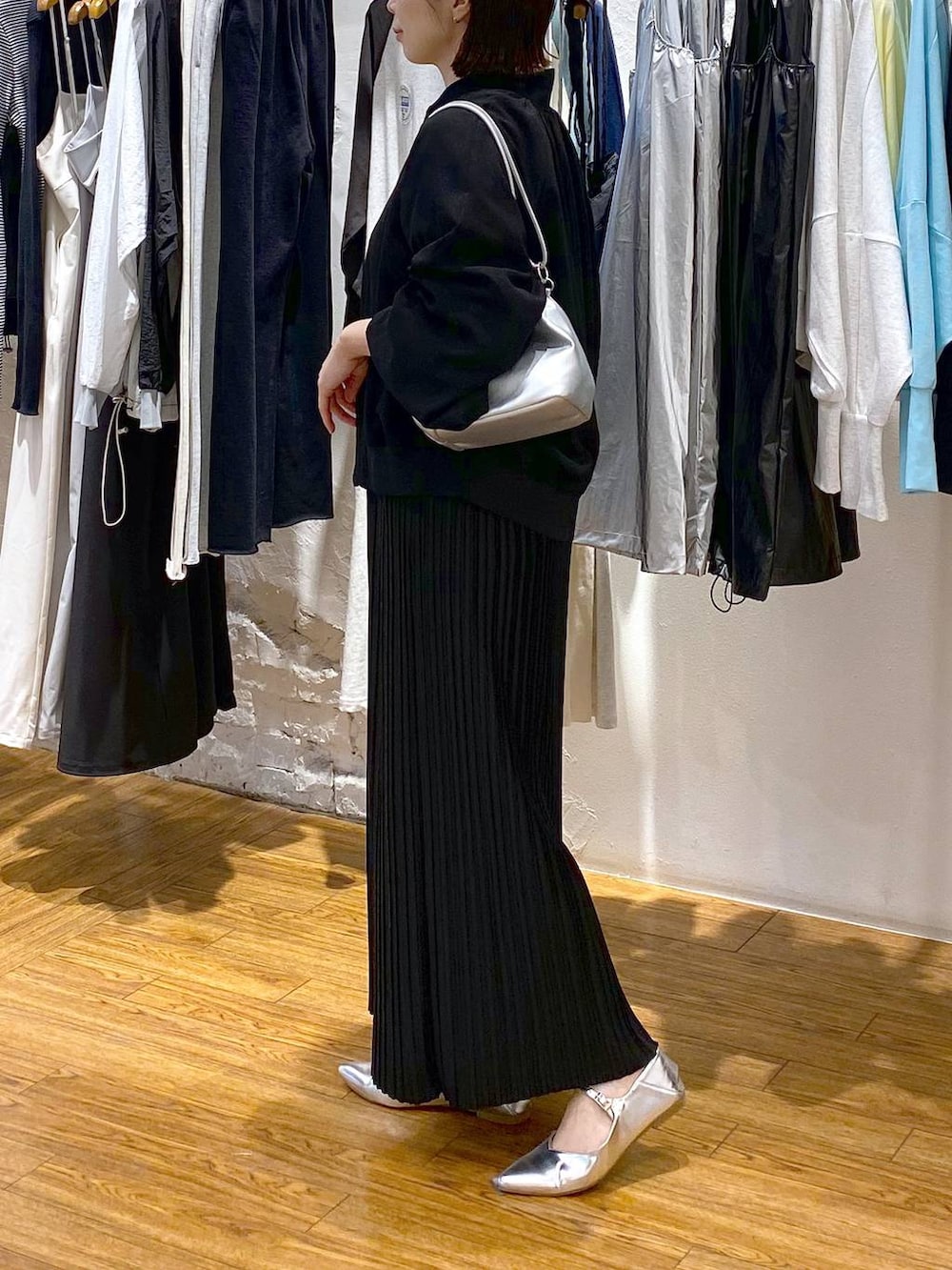 シルバー系のショルダーバッグ、ブラック系のスカート、グレー系のパンプスを着用したレディースの春コーディネートの3枚目の写真