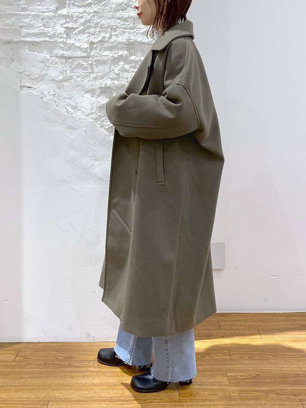 グリーン系のチェスターコート、グレー系のTシャツ/カットソー、ブラック系のブーツを着用したレディースの冬コーディネートの3枚目の写真