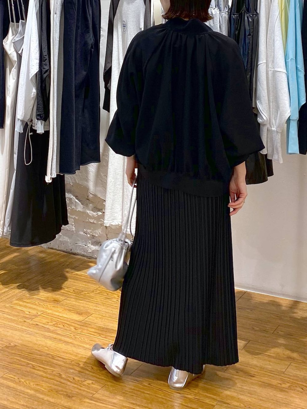 シルバー系のショルダーバッグ、ブラック系のスカート、グレー系のパンプスを着用したレディースの春コーディネートの4枚目の写真