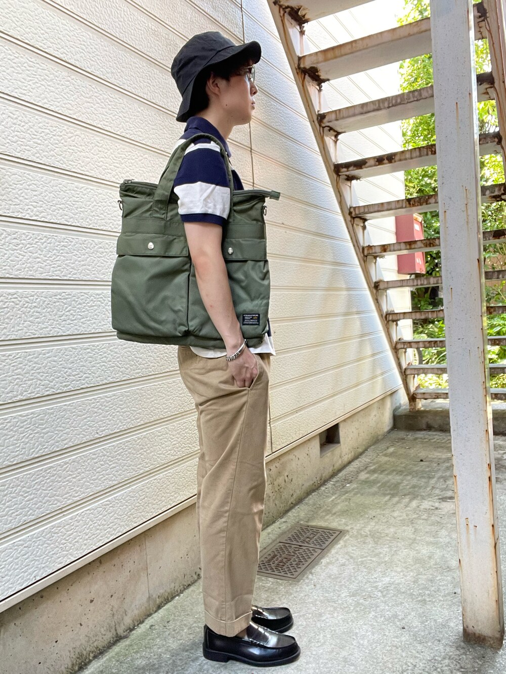 ブラック系のローファー、ベージュ系のチノパンツ、ホワイト系のポロシャツを着用したメンズの夏コーディネートの2枚目の写真