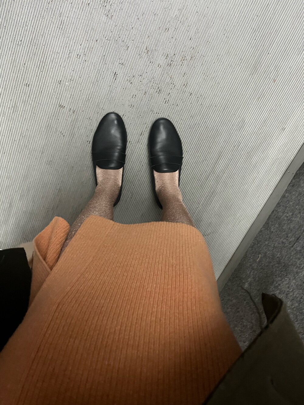 グレー系のニット/セーター、ブラック系のスカート、ブラック系のローファーを着用したレディースの冬コーディネートの2枚目の写真