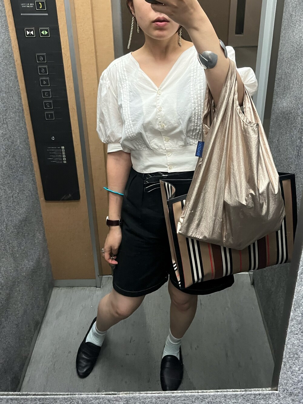 ベージュ系のシャツ/ブラウス、ブラック系のパンツ、ブラック系のローファーを着用したレディースの夏コーディネートの2枚目の写真