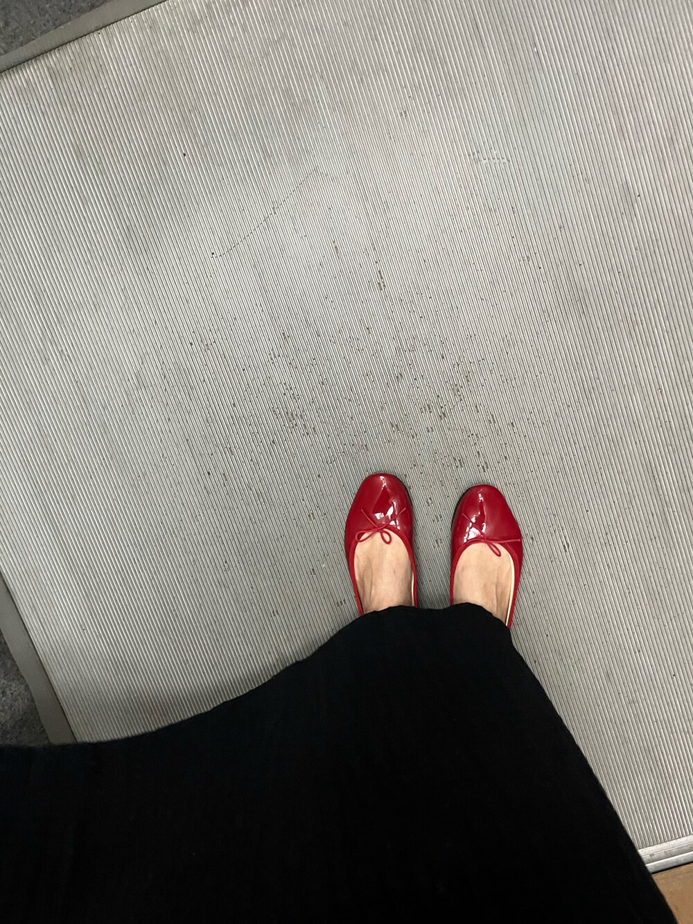 ブラック系のワンピース、ブラウン系のショルダーバッグ、レッド系のバレエシューズを着用したレディースの春コーディネートの2枚目の写真