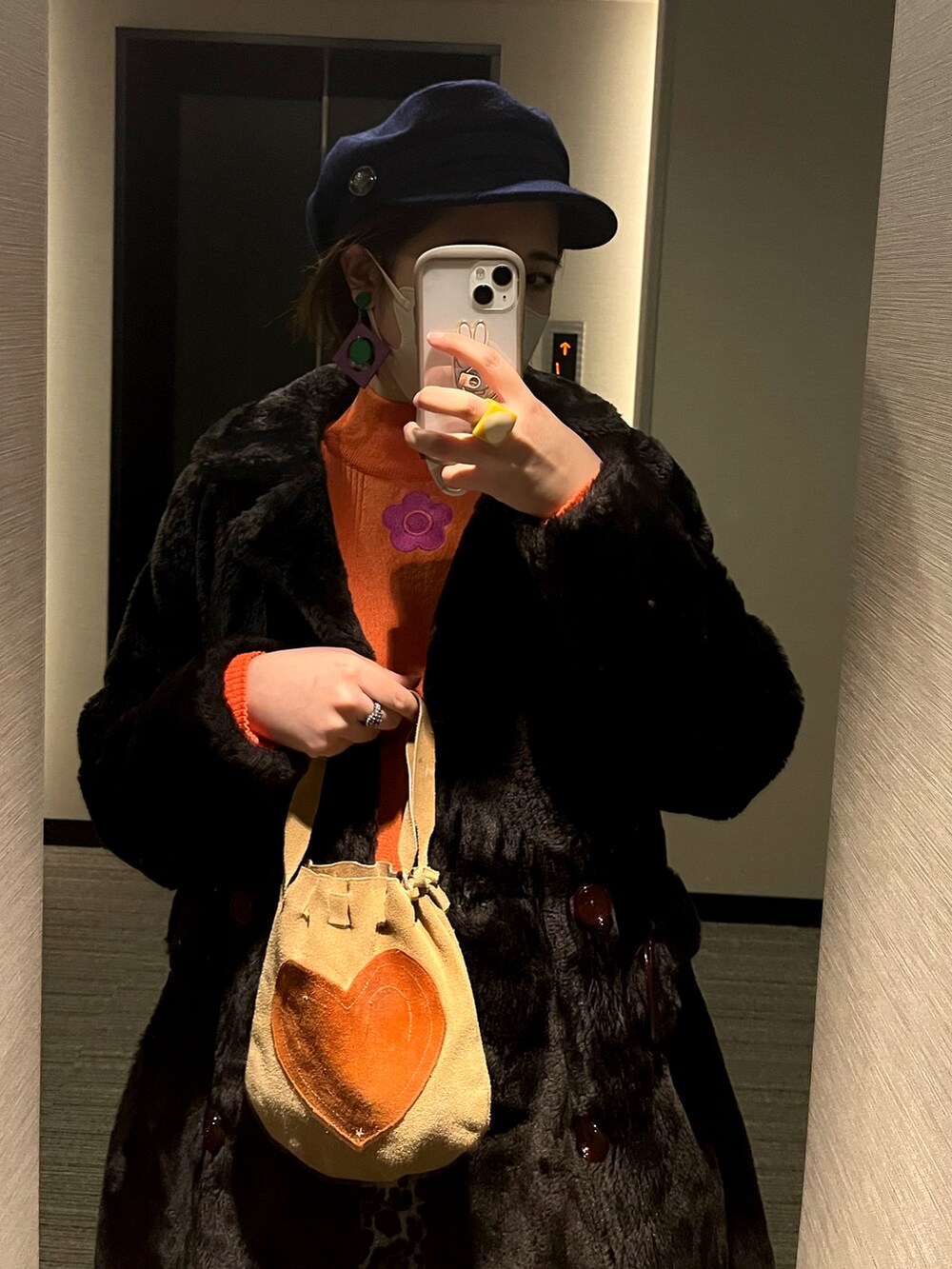 オレンジ系のニット/セーター、ブラック系のジャケット/アウター、ベージュ系のバッグを着用したレディースの冬コーディネートの2枚目の写真