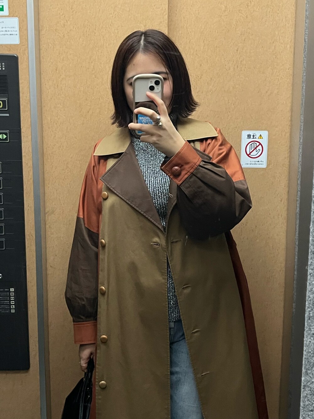 ベージュ系のトレンチコート、グレー系のニット/セーター、ブルー系のデニムパンツを着用したレディースの冬コーディネートの2枚目の写真