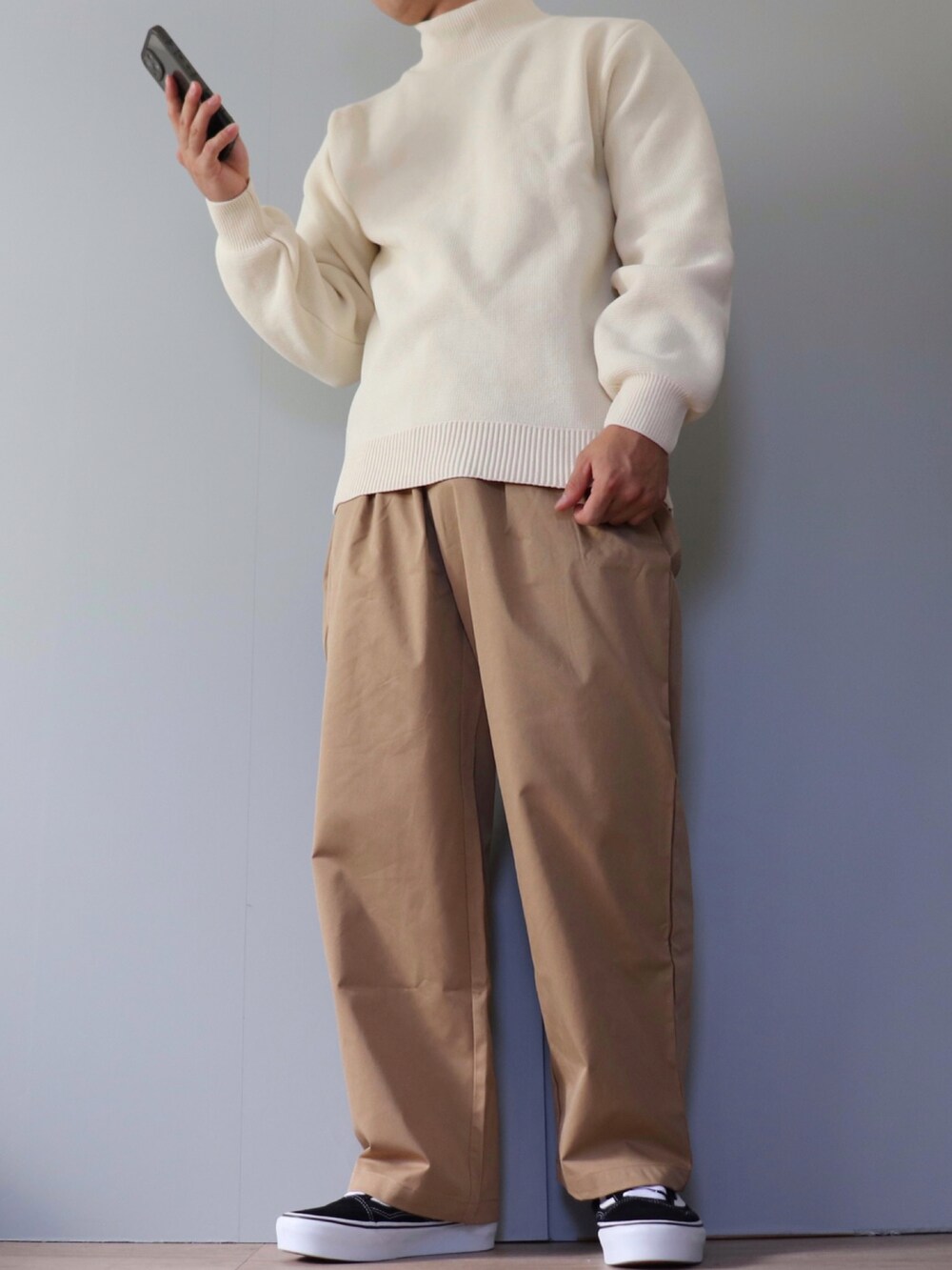 ホワイト系のニット/セーター、ベージュ系のチノパンツ、ブラック系のスニーカーを着用したメンズの秋コーディネートの2枚目の写真