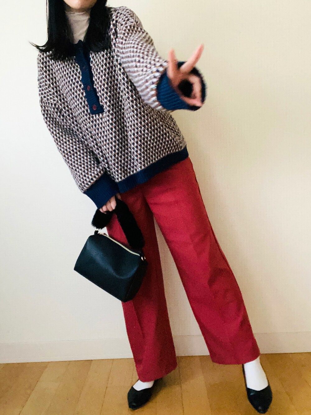 ブルー系のニット/セーター、レッド系のスラックス、ベージュ系のTシャツ/カットソーを着用したレディースの冬コーディネートの2枚目の写真