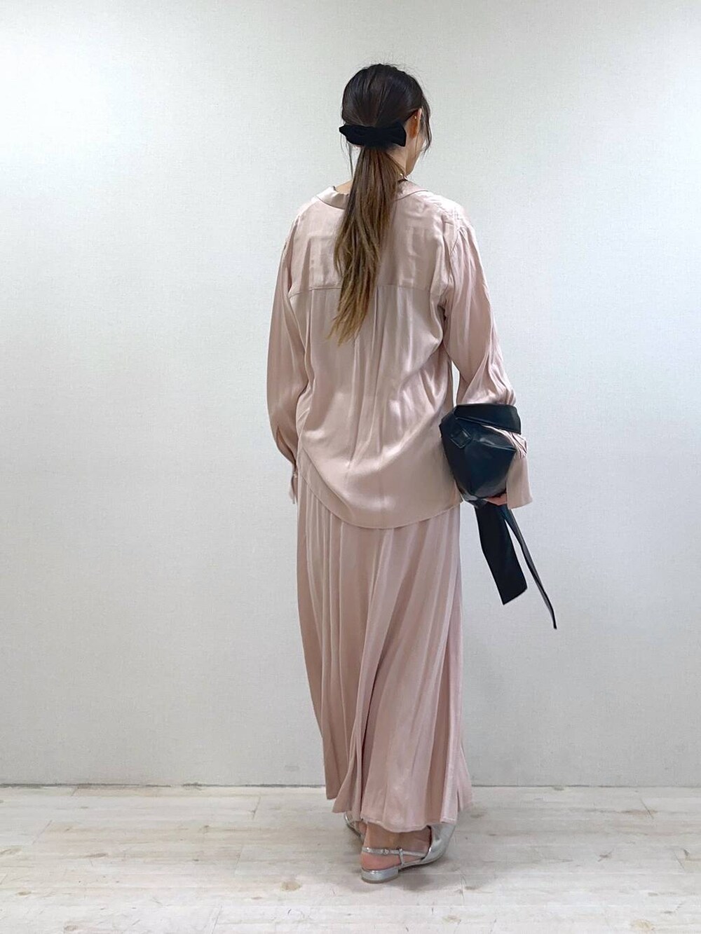 ブラック系のショルダーバッグ、シルバー系のパンプス、ピンク系のスカートを着用したレディースの冬コーディネートの3枚目の写真