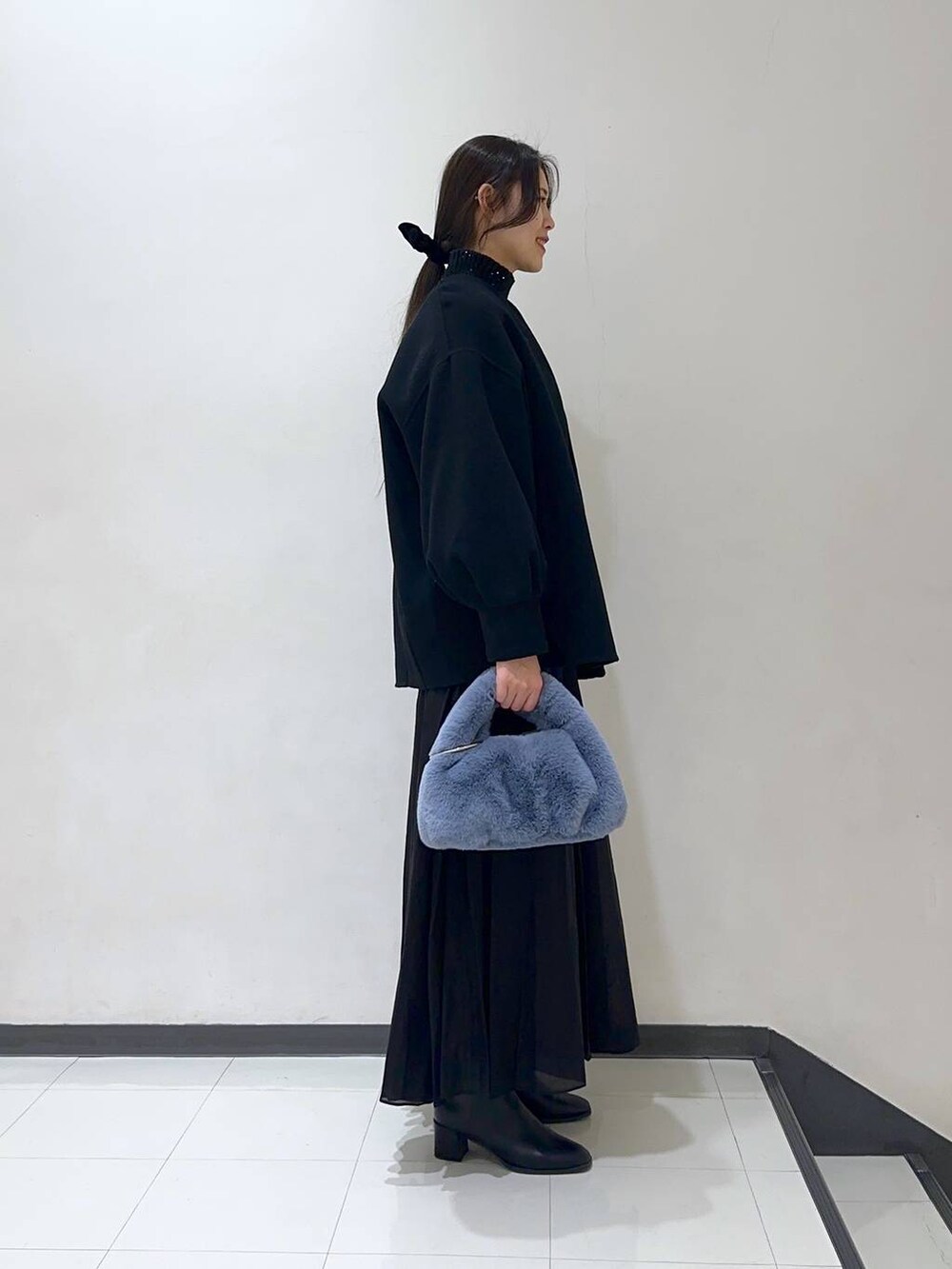 ブラック系のノーカラーコート、ブラック系のスカート、ブラック系のブーツを着用したレディースの冬コーディネートの2枚目の写真