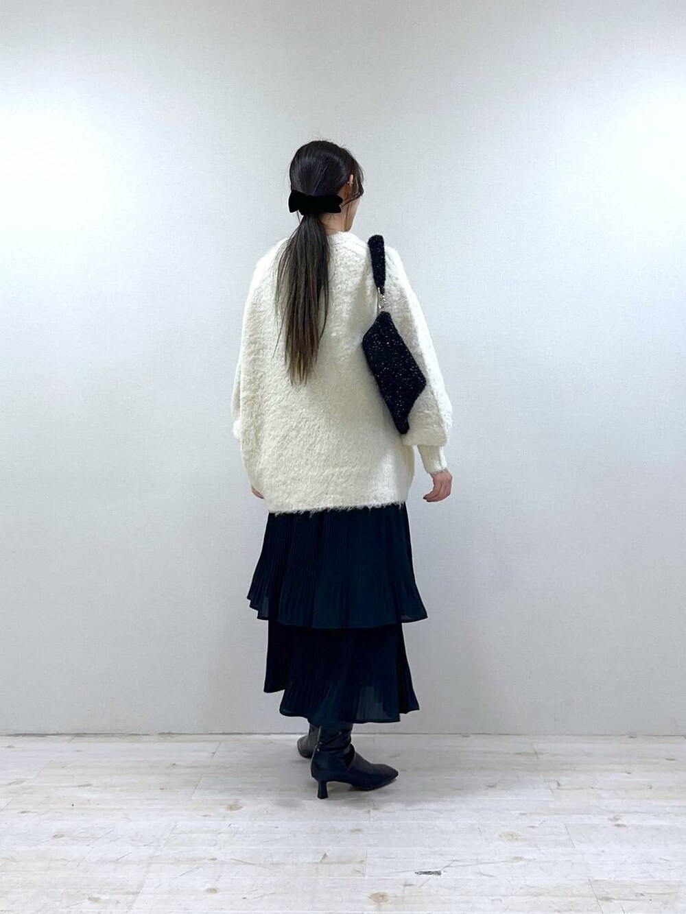 ブラック系のスカート、ブラック系のブーツ、ブラック系のクラッチバッグを着用したレディースの冬コーディネートの3枚目の写真