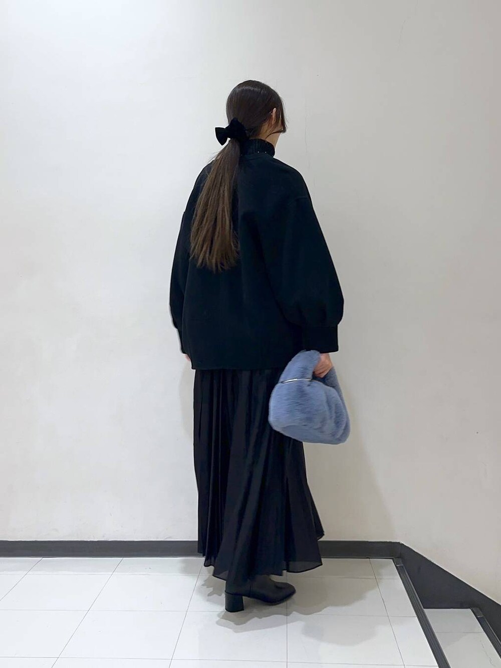 ブラック系のノーカラーコート、ブラック系のスカート、ブラック系のブーツを着用したレディースの冬コーディネートの3枚目の写真