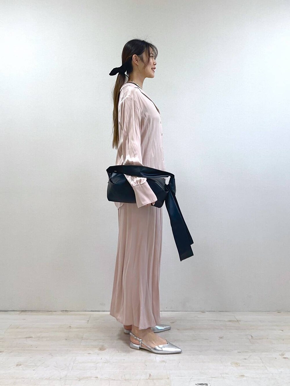 ブラック系のショルダーバッグ、シルバー系のパンプス、ピンク系のスカートを着用したレディースの冬コーディネートの2枚目の写真