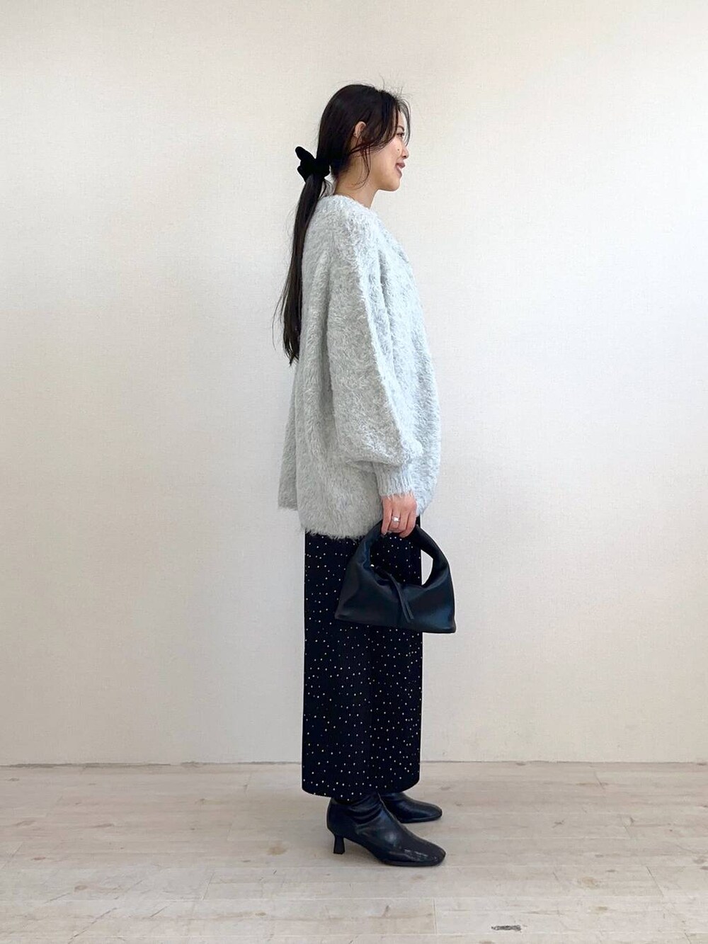 ブラック系のハンドバッグ、ブラック系のブーツ、グレー系のカーディガン/ボレロを着用したレディースの冬コーディネートの2枚目の写真