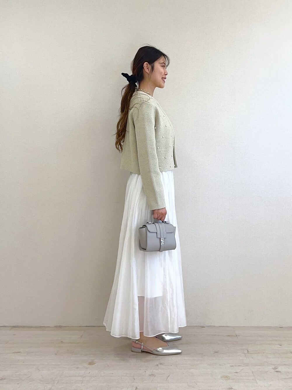 ベージュ系のカーディガン/ボレロ、ホワイト系のスカート、シルバー系のパンプスを着用したレディースの冬コーディネートの2枚目の写真