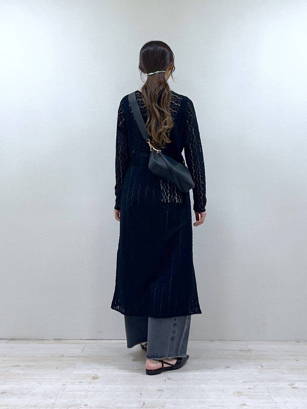 ブラック系のショルダーバッグ、グレー系のデニムパンツ、ブラック系のワンピースを着用したレディースの冬コーディネートの3枚目の写真