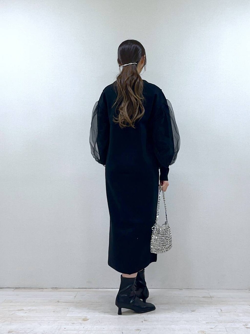 ブラック系のブーツ、ブラック系のワンピース、シルバー系のショルダーバッグを着用したレディースの冬コーディネートの3枚目の写真