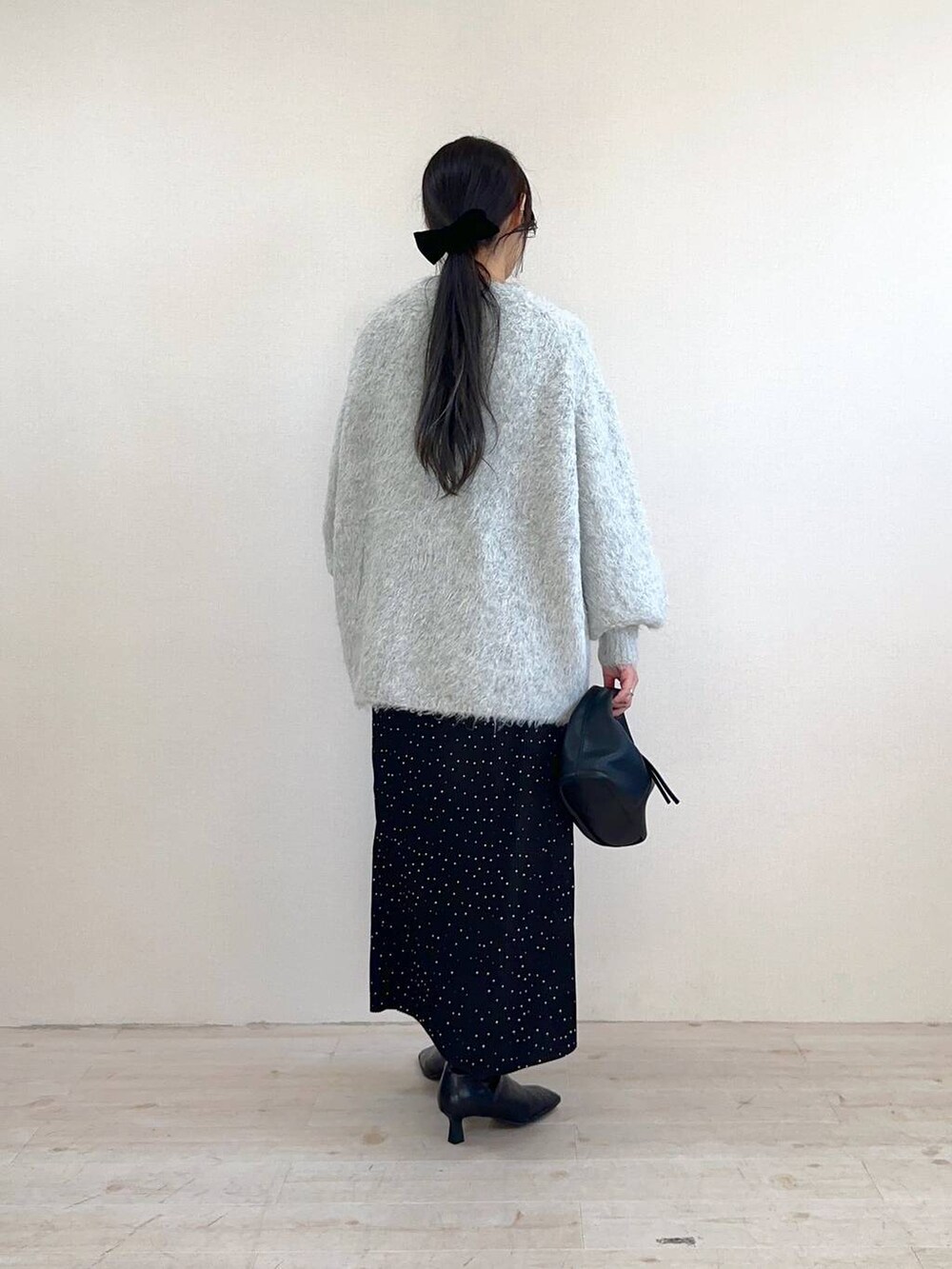 ブラック系のハンドバッグ、ブラック系のブーツ、グレー系のカーディガン/ボレロを着用したレディースの冬コーディネートの3枚目の写真