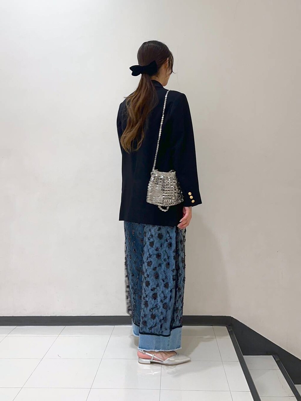 ブルー系のデニムパンツ、ブラック系のテーラードジャケット、シルバー系のショルダーバッグを着用したレディースの冬コーディネートの3枚目の写真