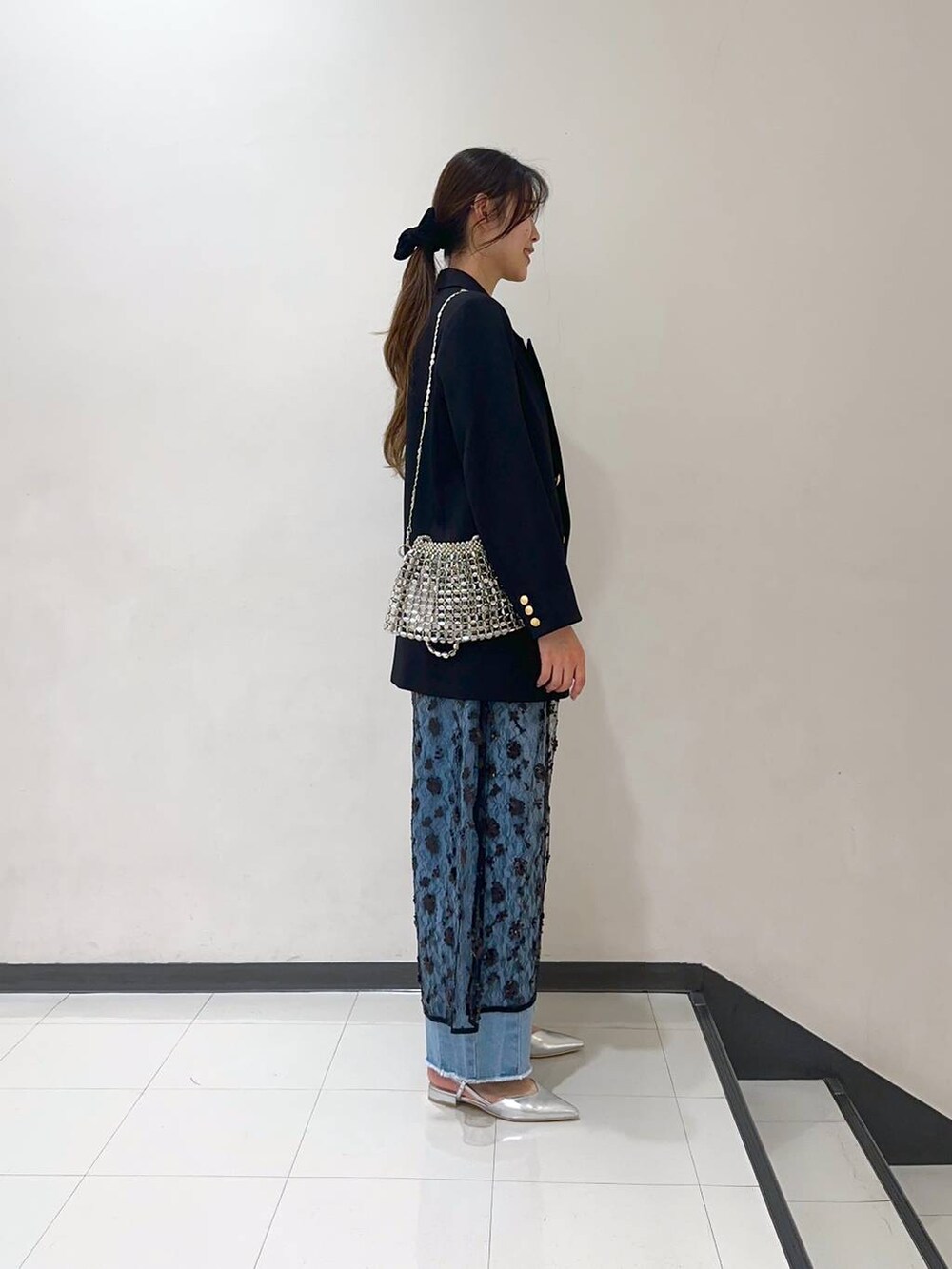 ブルー系のデニムパンツ、ブラック系のテーラードジャケット、シルバー系のショルダーバッグを着用したレディースの冬コーディネートの2枚目の写真