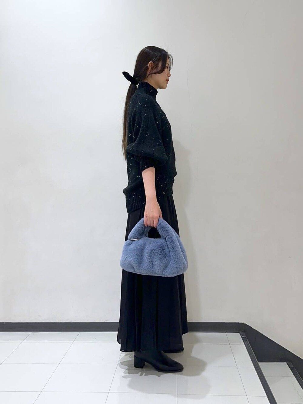 ブラック系のスカート、ブラック系のブーツ、ブラック系のニット/セーターを着用したレディースの冬コーディネートの2枚目の写真