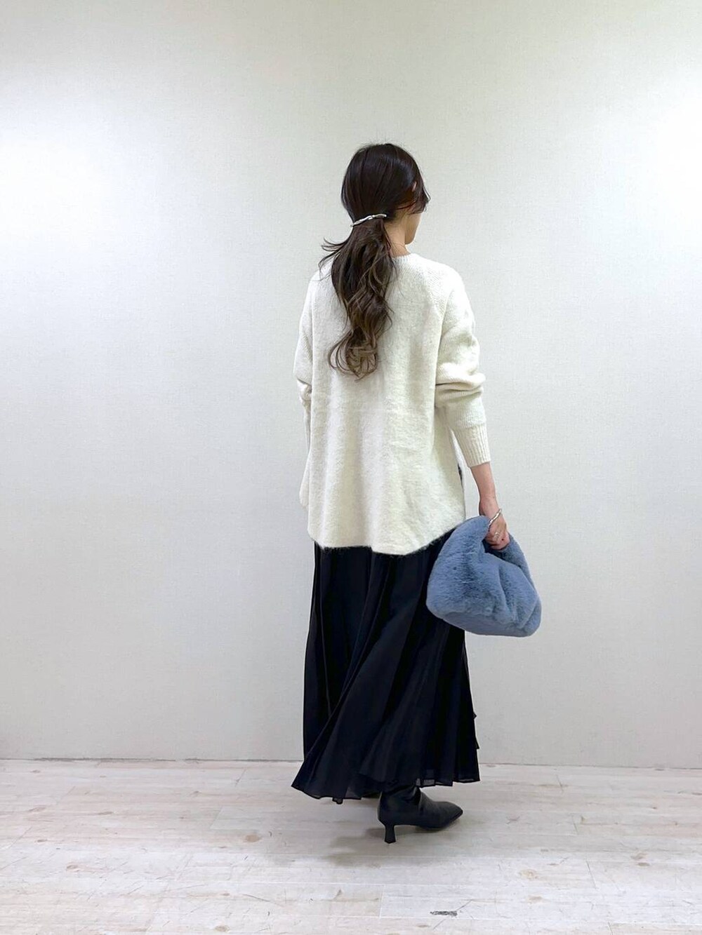 ホワイト系のニット/セーター、ブラック系のスカート、ブラック系のブーツを着用したレディースの冬コーディネートの3枚目の写真