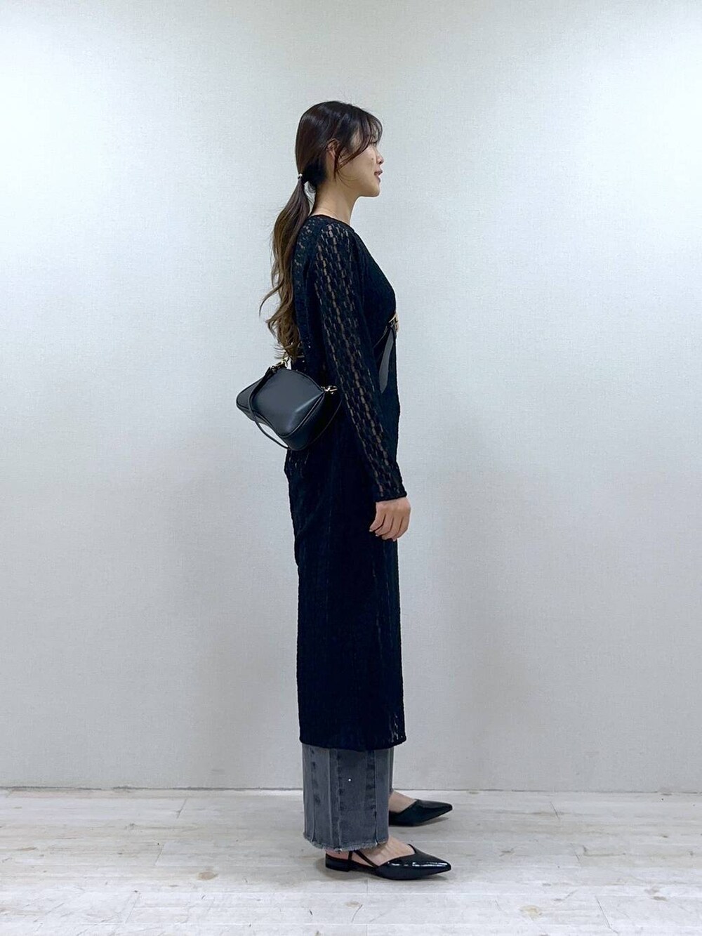 ブラック系のショルダーバッグ、グレー系のデニムパンツ、ブラック系のワンピースを着用したレディースの冬コーディネートの2枚目の写真