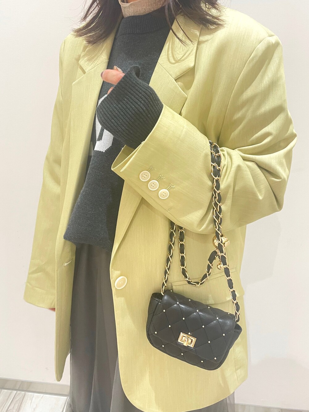 グレー系のスカート、グリーン系のテーラードジャケット、ブラック系のニット/セーターを着用したレディースの冬コーディネートの2枚目の写真