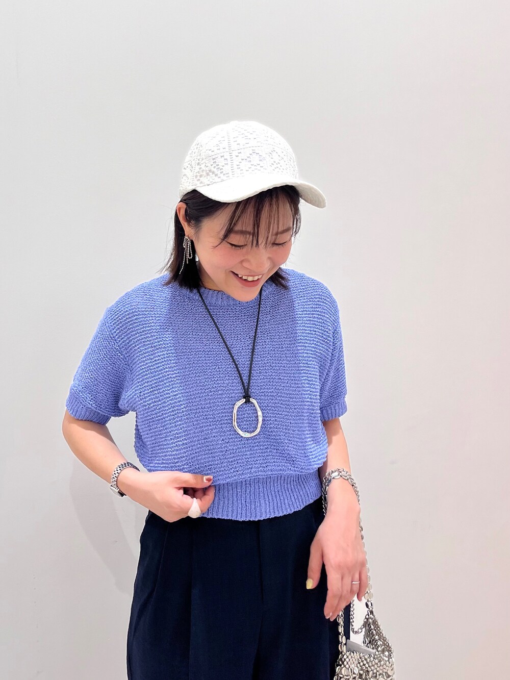 ブルー系のニット/セーター、ブルー系のスラックス、シルバー系のショルダーバッグを着用したレディースの春コーディネートの3枚目の写真