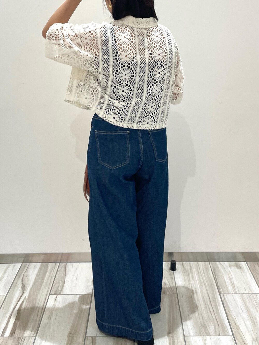 ブルー系のデニムパンツ、ブラウン系のショルダーバッグ、ホワイト系のカーディガン/ボレロを着用したレディースの春コーディネートの3枚目の写真