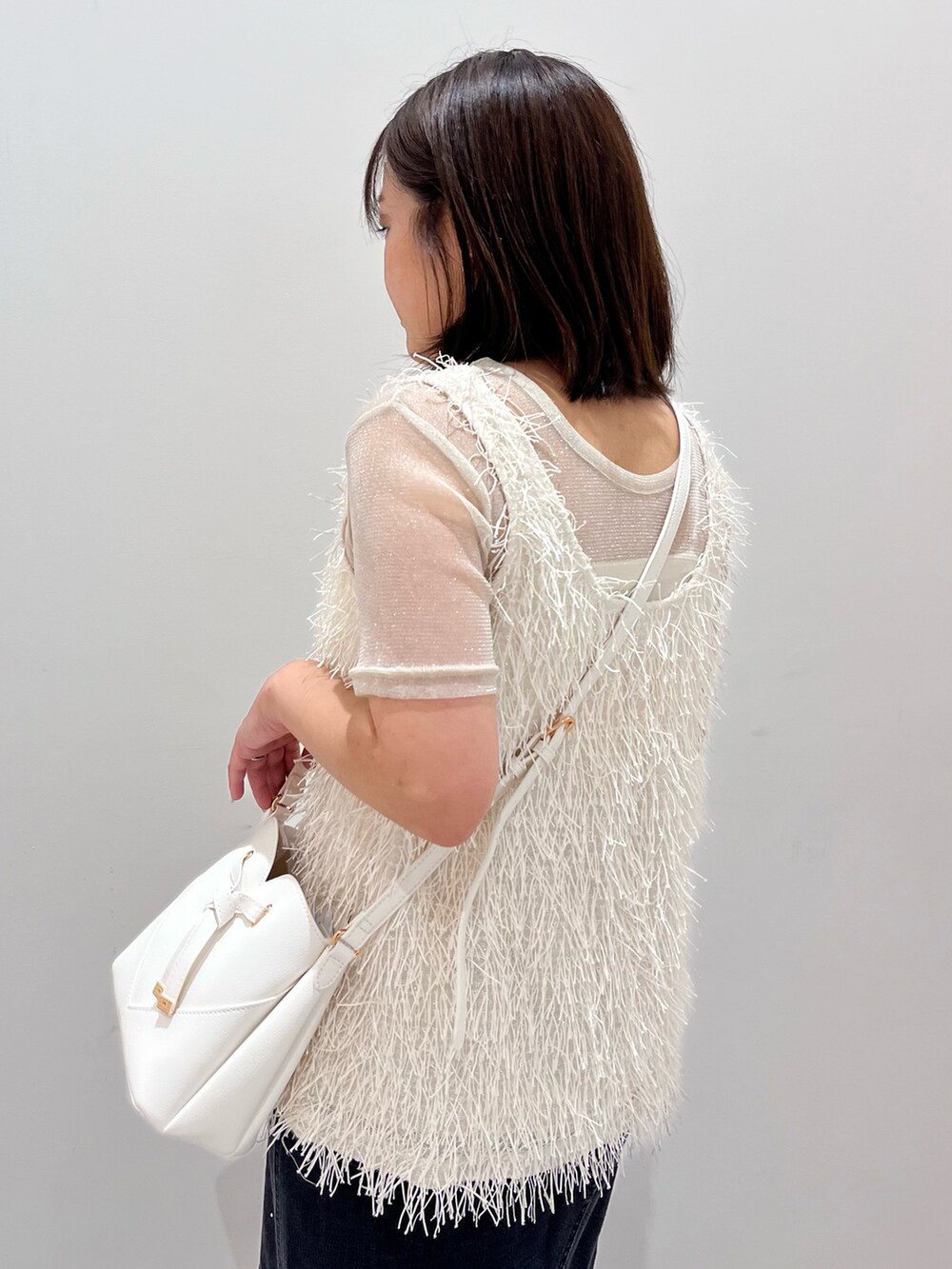 グレー系のタンクトップ、ブラック系のデニムスカート、ホワイト系のショルダーバッグを着用したレディースの夏コーディネートの4枚目の写真