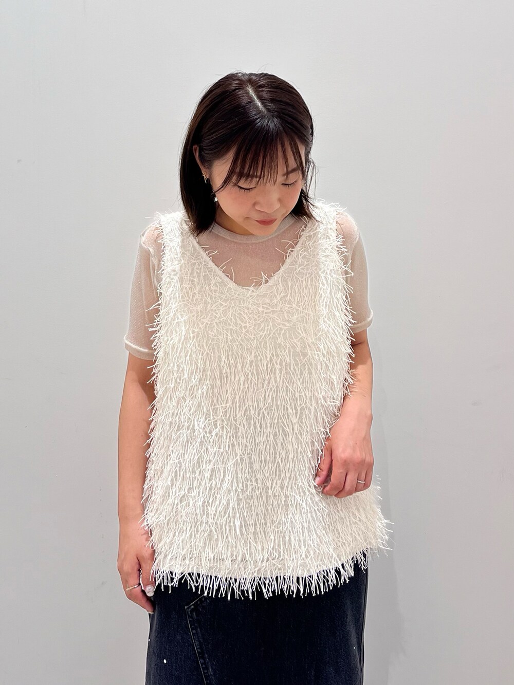 グレー系のタンクトップ、ブラック系のデニムスカート、ホワイト系のショルダーバッグを着用したレディースの夏コーディネートの3枚目の写真