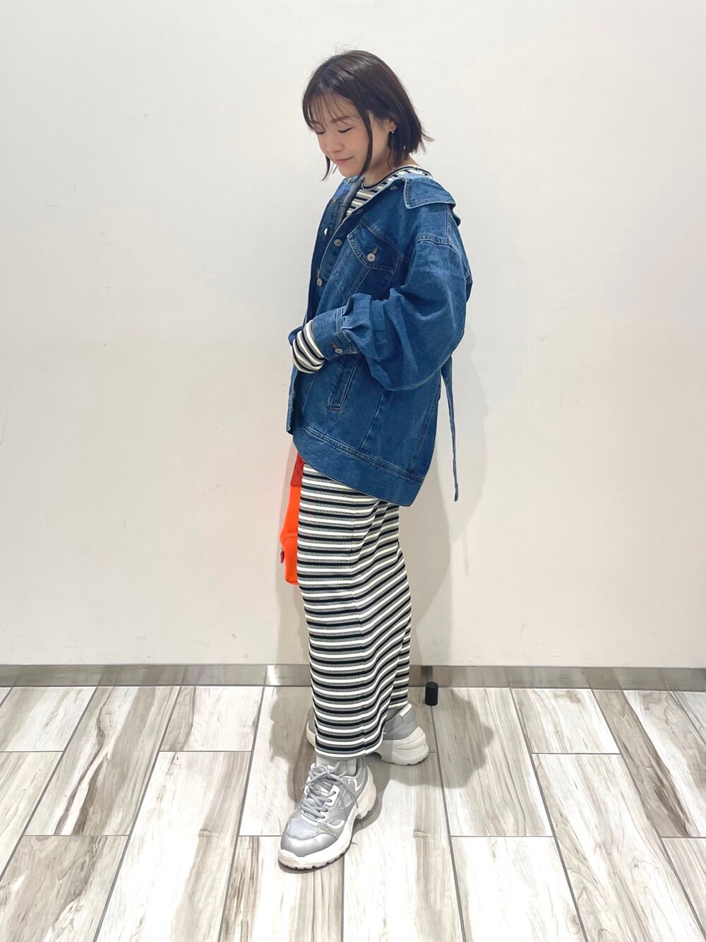 オレンジ系のハンドバッグ、ブラック系のワンピース、ブルー系のデニムジャケットを着用したレディースの春コーディネートの2枚目の写真