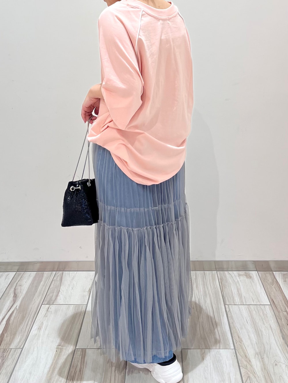 ブラック系のショルダーバッグ、グレー系のスカート、ブルー系のデニムパンツを着用したレディースの夏コーディネートの3枚目の写真