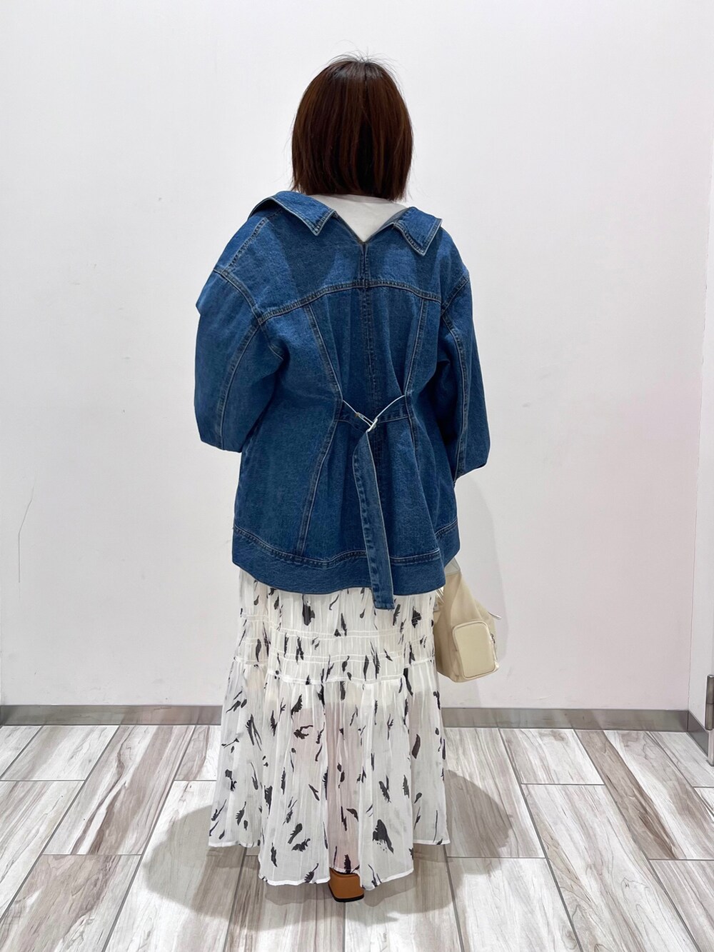 ブルー系のデニムジャケット、ブルー系のTシャツ/カットソー、ホワイト系のスカートを着用したレディースの春コーディネートの3枚目の写真