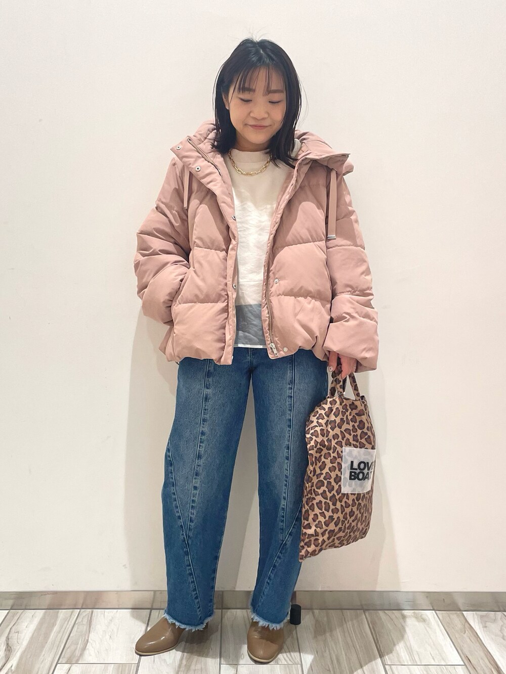 ピンク系のダウンジャケット/コート、ブルー系のデニムパンツ、ブラウン系のトートバッグを着用したレディースの冬コーディネートの2枚目の写真