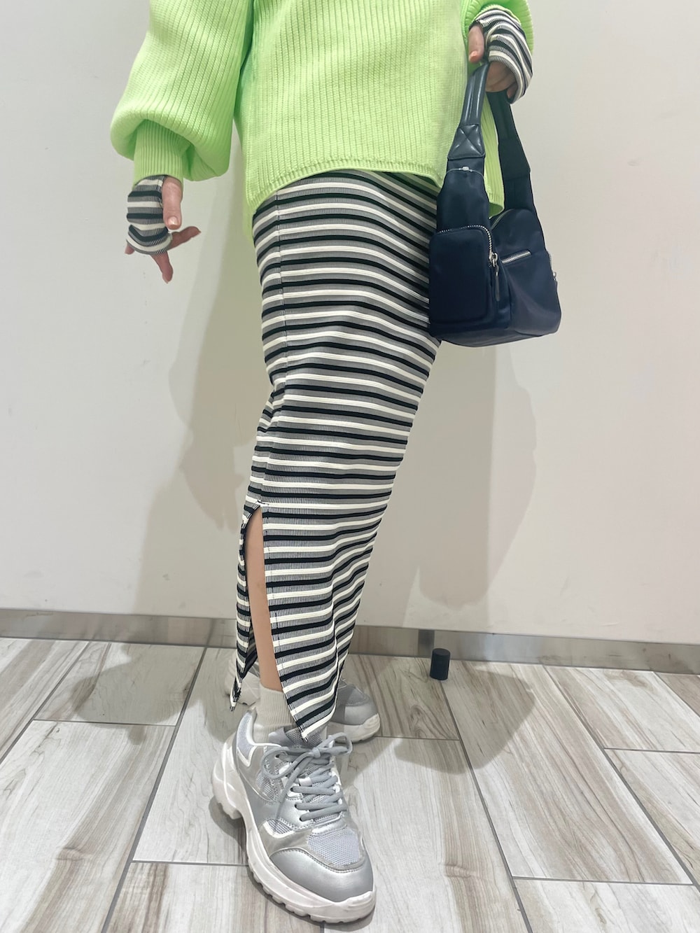 グリーン系のニット/セーター、ブラック系のワンピース、ブルー系のハンドバッグを着用したレディースの春コーディネートの5枚目の写真