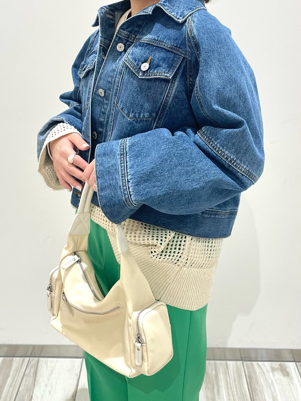 シルバー系のショルダーバッグ、グリーン系のスラックス、ホワイト系のニット/セーターを着用したレディースの春コーディネートの4枚目の写真