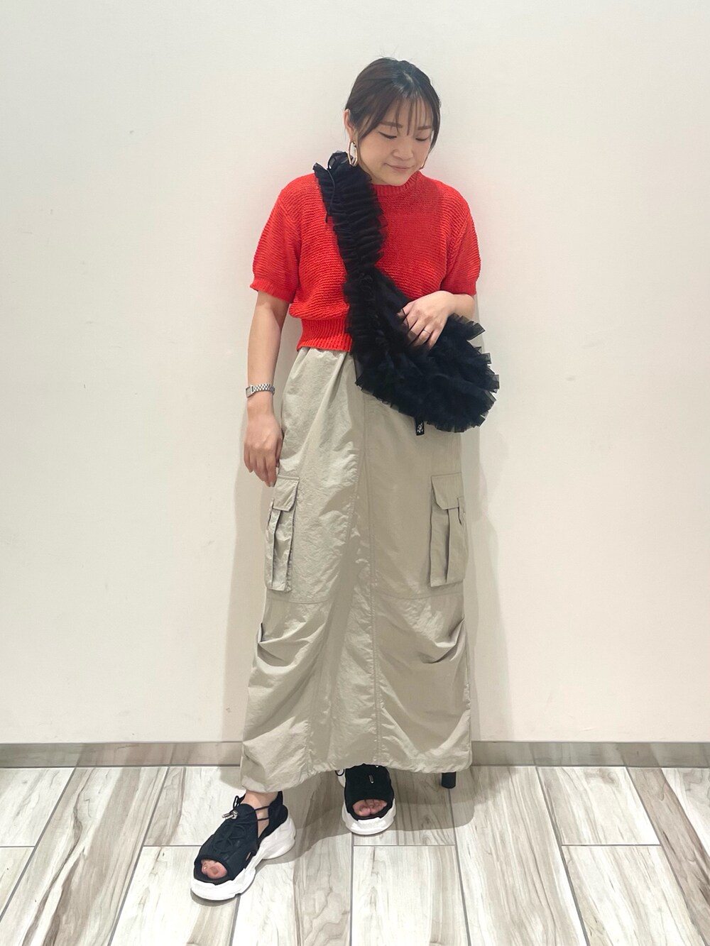 レッド系のニット/セーター、ブラック系のショルダーバッグを着用したレディースの春コーディネートの2枚目の写真