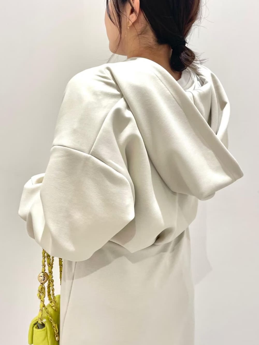 ホワイト系のワンピース、ブルー系のデニムパンツ、イエロー系のショルダーバッグを着用したレディースの冬コーディネートの3枚目の写真