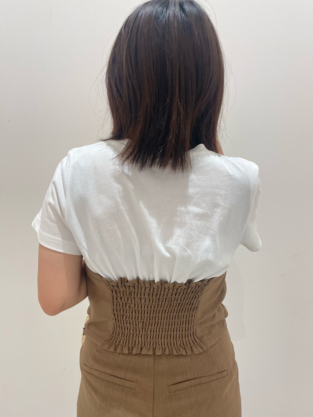 ブラウン系のスラックスを着用したレディースの夏コーディネートの4枚目の写真