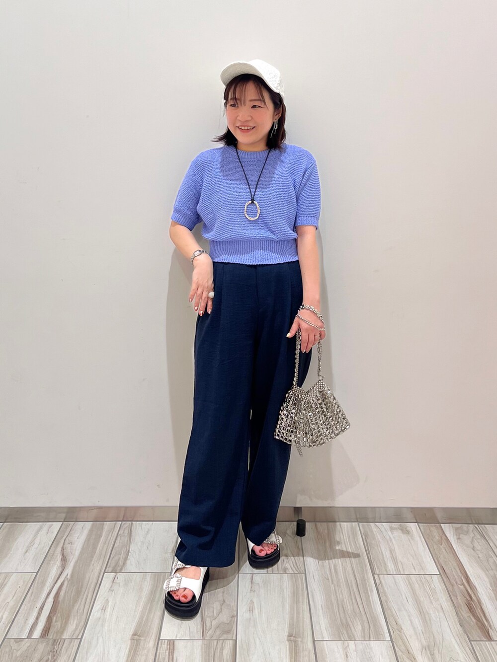 ブルー系のニット/セーター、ブルー系のスラックス、シルバー系のショルダーバッグを着用したレディースの春コーディネートの2枚目の写真